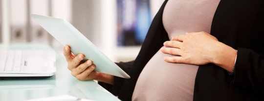 Pregnant woman reading about maternity pay and other maternity procedures such as parental leave in her contract