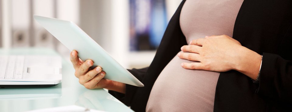 Pregnant woman reading about maternity pay and other maternity procedures such as parental leave in her contract