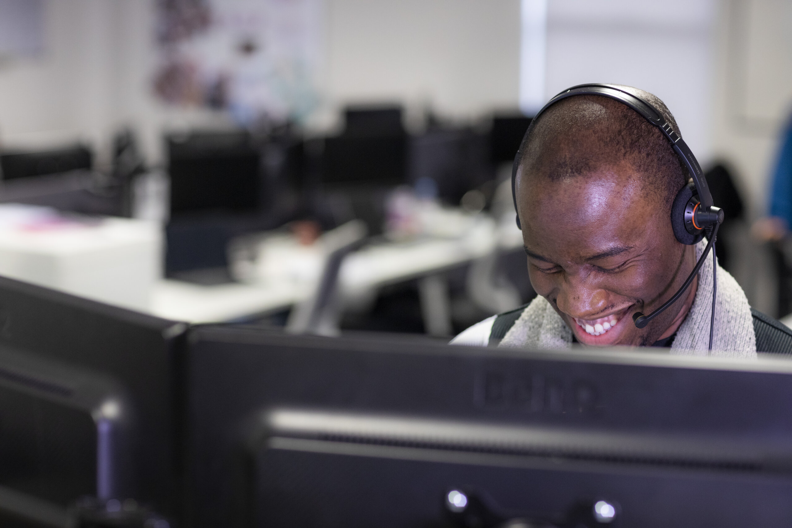 Man smiling wearing a headset whilst talking on the phones