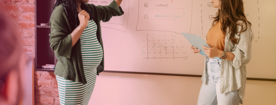 Pregnant employee giving a company presentation on a whiteboard